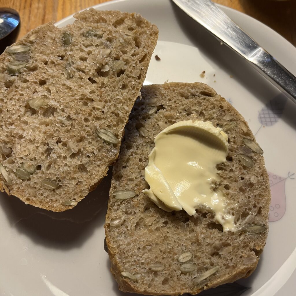 Overskåret bolle på en tallerken, den ene halve har en smørklat på